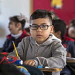 A kid in a classroom, looking at the camera